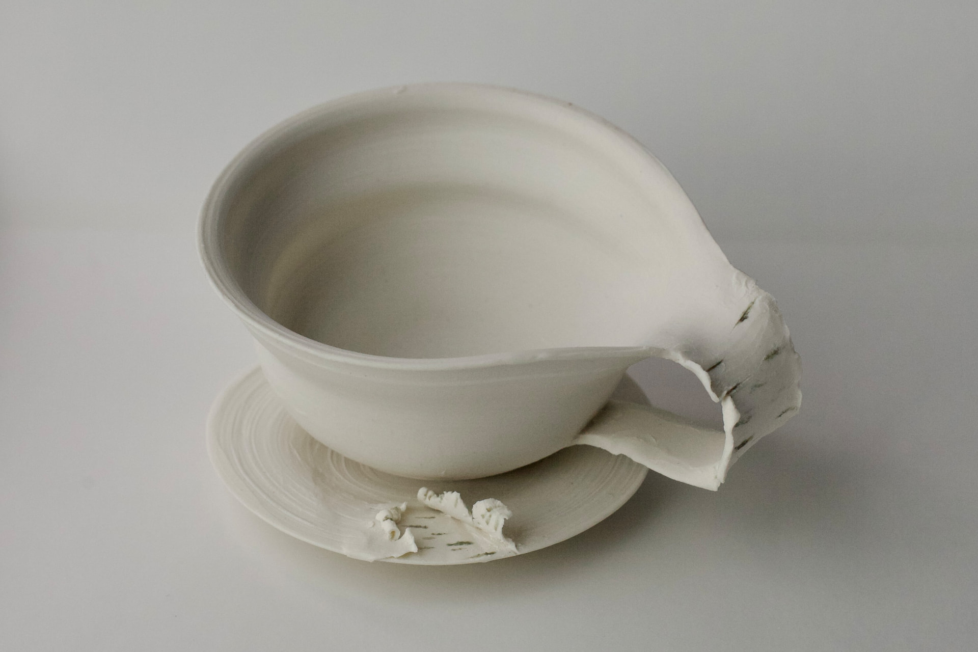 Fine porcelain cup and saucer with a peeled birch-bark handle, seen from above