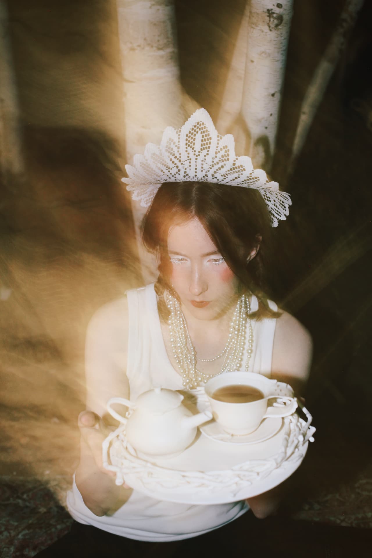 Double-exposure film portrait — a figure in a lace kokoshnik and pearl necklaces holding the porcelain tea set