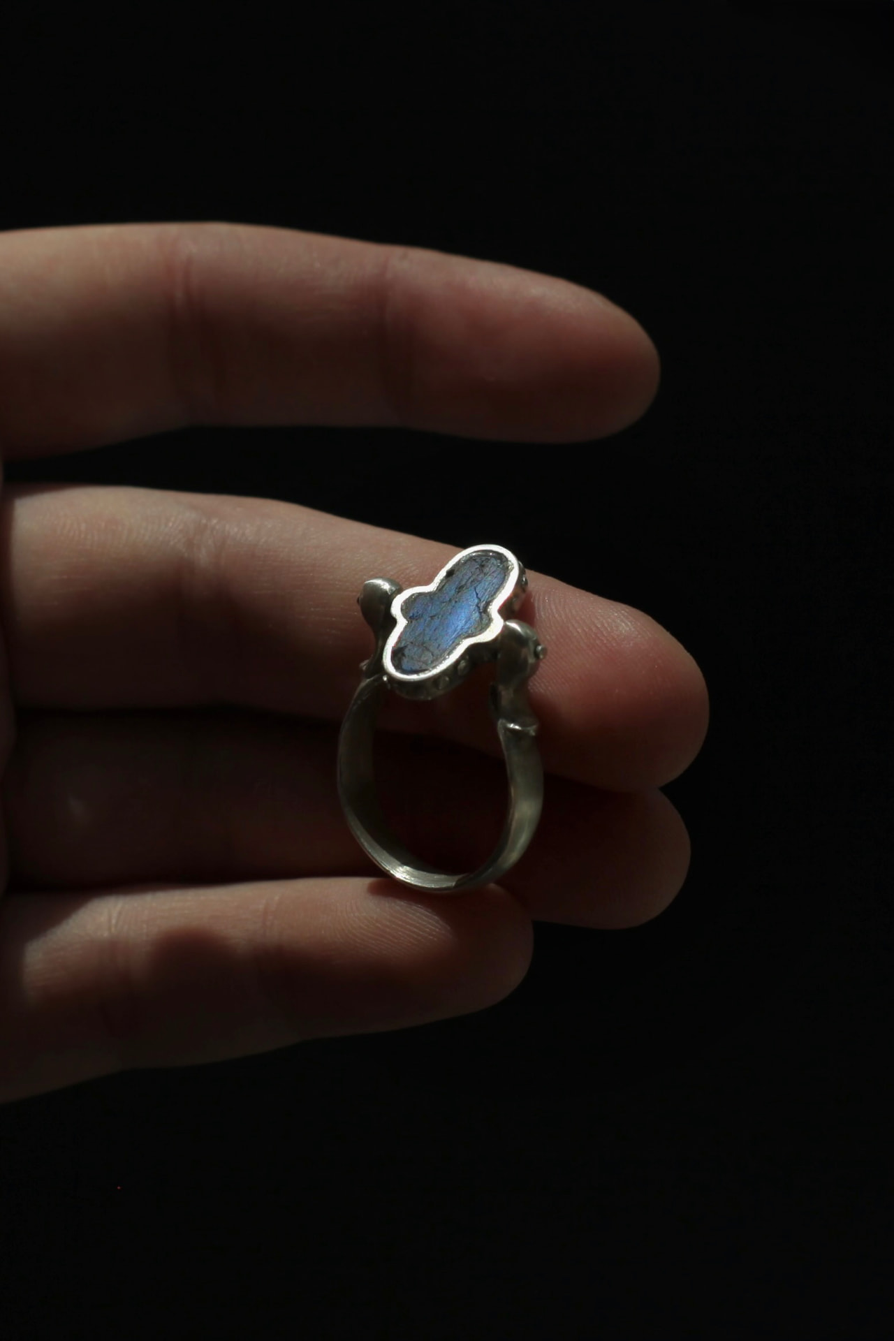 Reversible silver ring with a labradorite stone held between the fingers